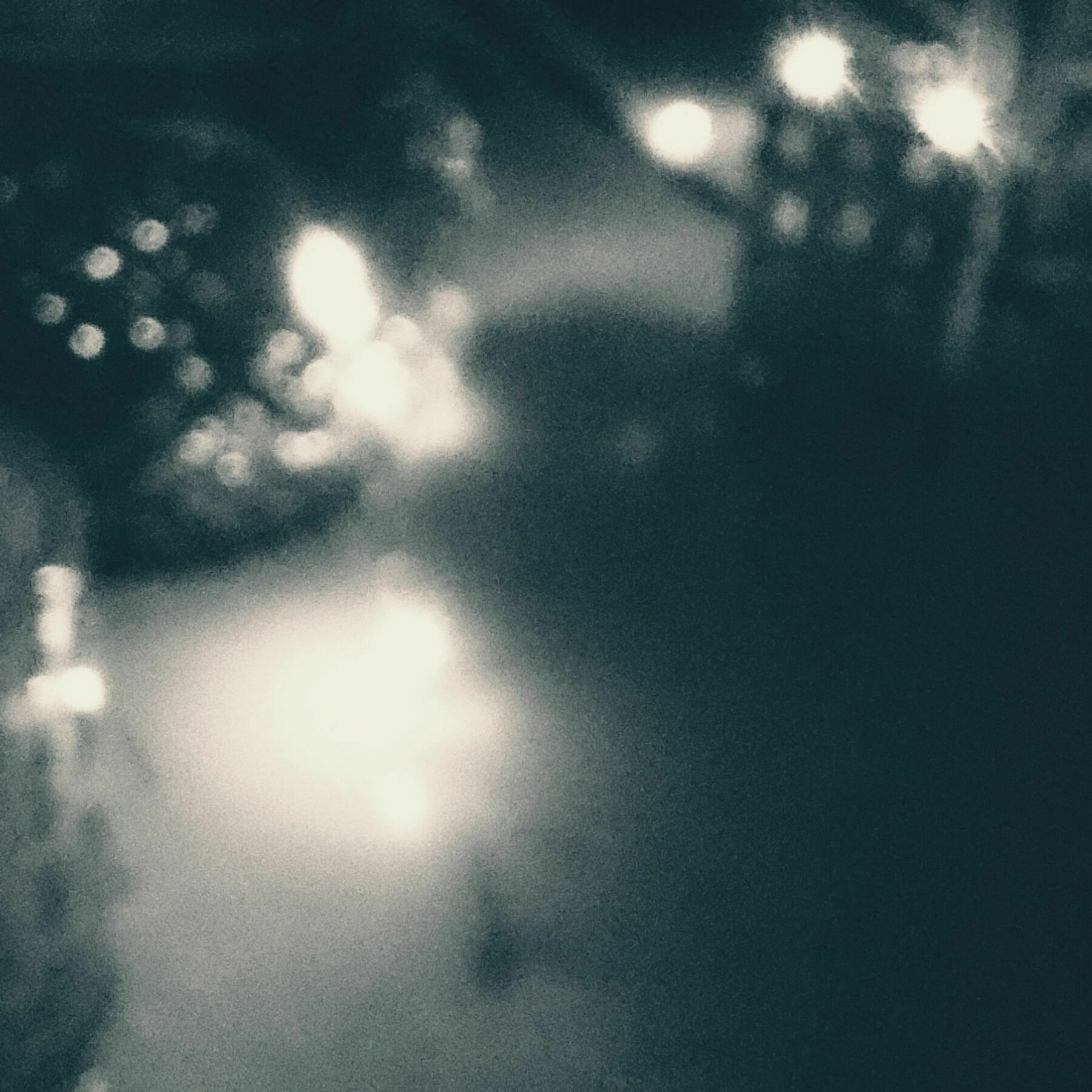 Blurred monochrome shot of lights and structures on a windowpane.